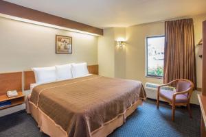 una habitación de hotel con una cama grande y una silla en Travelodge by Wyndham Fort Myers Airport, en Fort Myers