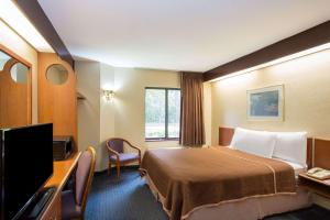 a hotel room with a bed and a flat screen tv at Travelodge by Wyndham Fort Myers Airport in Fort Myers