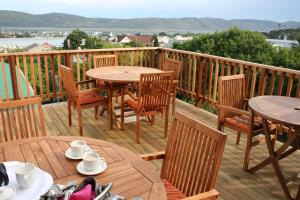 a wooden deck with tables and chairs on it at Knysna Manor House in Knysna