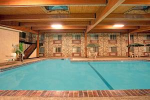 a large pool in a hotel with tables and chairs at Super 8 by Wyndham Monticello in Monticello