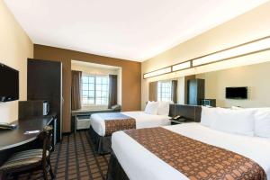 Habitación de hotel con 2 camas y escritorio en Microtel Inn and Suites Eagle Pass en Eagle Pass