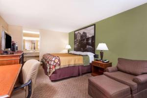 a hotel room with a bed and a chair at Super 8 by Wyndham Macon West in Macon