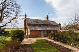 Plum Cottage - Vivre Retreats في ويمبورن مينستر: منزل من الطوب القديم في وسط الميدان