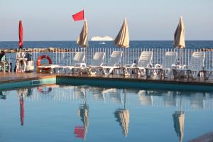 a pool with chairs and the ocean in the background at Hotel Mayola in San Bartolomeo al Mare