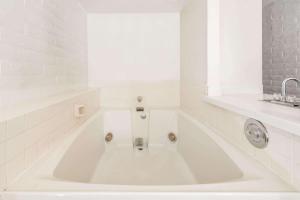 uma banheira branca na casa de banho com um lavatório em Knights Inn Dayton by Miller Lane em Dayton