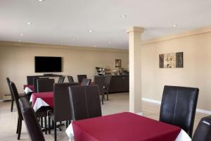 a dining room with tables and chairs and a flat screen tv at Travelodge by Wyndham Kapuskasing in Kapuskasing