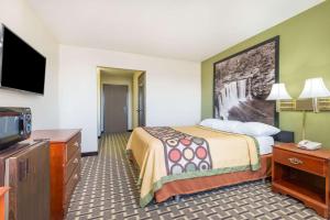 a hotel room with a bed and a flat screen tv at Super 8 by Wyndham Madison IN in Madison