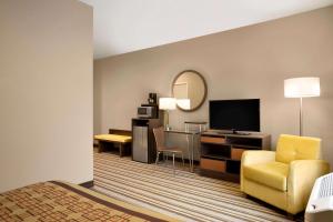 a hotel room with a bed and a desk with a television at Super 8 by Wyndham Hershey Chocolate Avenue in Hershey