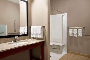 ein Badezimmer mit Waschbecken und Dusche mit Spiegel in der Unterkunft Super 8 by Wyndham Hershey Chocolate Avenue in Hershey