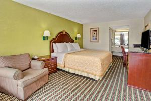 a hotel room with a bed and a chair at Travelodge by Wyndham Sellersburg in Sellersburg