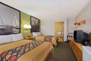 a hotel room with two beds and a flat screen tv at Super 8 by Wyndham Huntersville/Charlotte Area in Huntersville
