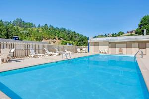 a large swimming pool with chairs and a fence at Travelodge by Wyndham Rapid City in Rapid City
