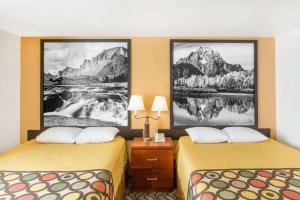 two beds in a hotel room with paintings on the wall at Super 8 by Wyndham Diamondville Kemmerer in Kemmerer