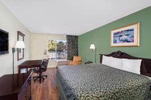 a hotel room with a bed and a desk and a window at Travelodge by Wyndham Fort Myers North in North Fort Myers