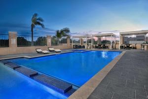 una gran piscina azul con sillas y mesas. en Hawthorn Suites by Wyndham McAllen, en McAllen