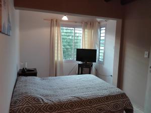 1 dormitorio con 1 cama y TV de pantalla plana en Departamentos Angenino Lujan en Luján de Cuyo