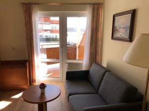 ein Wohnzimmer mit einem Sofa, einem Tisch und einem Fenster in der Unterkunft Hotel Garni Seeschlösschen in Ostseebad Kölpinsee