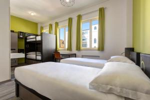 2 camas en una habitación con paredes y ventanas amarillas en The RomeHello, en Roma