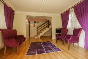 a living room with purple chairs and a staircase at PİA mya HOTEL in Alasehir