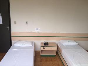 a room with two beds and a table between them at Hotel Real in Petrolina