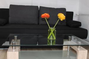 a vase with flowers on a glass table in front of a couch at Gasthof Rössle Ochsenwang in Bissingen an der Teck