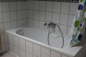 a bath tub in a bathroom with a shower curtain at Gasthof Rössle Ochsenwang in Bissingen an der Teck +25 photos