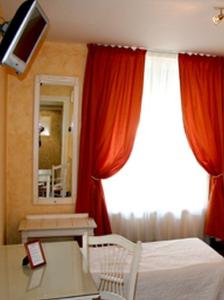 a bedroom with a bed and a window with red curtains at La Maison Blanche in Romanèche-Thorins