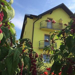 Perušić的住宿－阿巴托特羅斯住宿加早餐公里，黄色建筑,设有两个阳台,鲜花盛开