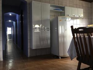 a kitchen with a white refrigerator in a room at La Melangerie - Hostel in Bertioga