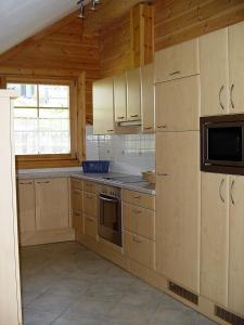 a kitchen with wooden cabinets and a microwave at Blockhaus Royer in Ramsau am Dachstein
