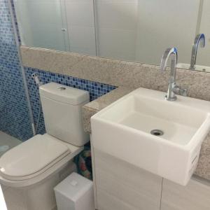 a bathroom with a white toilet and a sink at Nannai Residence in Porto De Galinhas