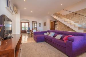 - un canapé violet dans un salon avec un escalier dans l'établissement Ca Na Nyola, à Montuiri