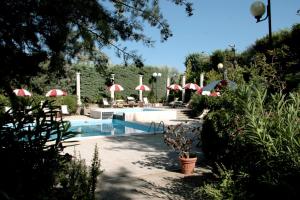 a pool with red and white umbrellas and chairs and a pool at Residence Villa Agrimare in Vieste