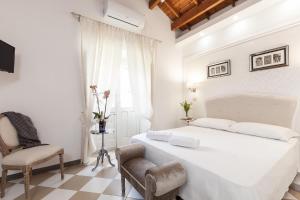 a white bedroom with a large bed and a chair at B&B San Giacomo in Cagliari