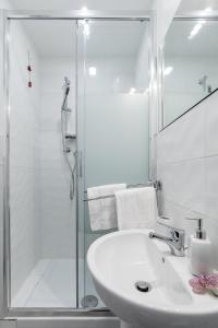 a white bathroom with a shower and a sink at B&B San Giacomo in Cagliari