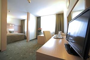 イェレニャ・グラにあるHotel Cieplice MEDI & SPAのテレビとベッドが備わるホテルルームです。