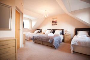 um quarto no sótão com 2 camas e um lustre em Ballas Farm Country Guest House em Bridgend