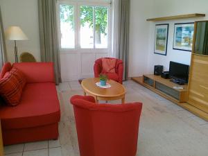 sala de estar con sillas rojas, mesa y TV en Villa Caprivi - Ferienwohnung 6 en Neuhof