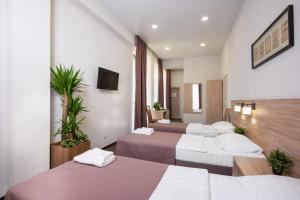 ein Hotelzimmer mit 4 Betten und einem TV in der Unterkunft Hotel Pelican in Krasnodar