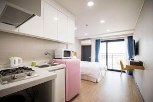 a kitchen with a pink refrigerator next to a bed at W Ocean Pension in Seogwipo