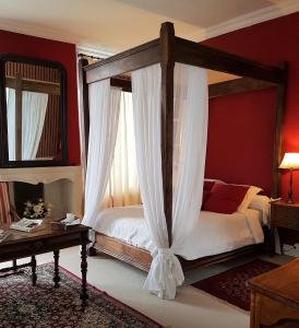 a bedroom with a canopy bed and a table at Château de Beaulieu in Saumur