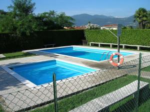 a blue swimming pool with a fence around it at Nicole 2 in Germignaga