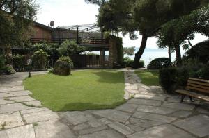 un jardín con un banco y una pasarela con césped en casa vacanze argentarola, en Porto Santo Stefano