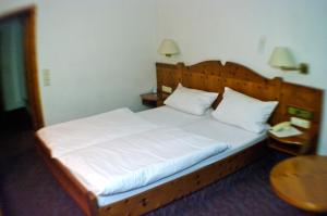 a bed with a white comforter and pillows at Gasthof zum Kauzen in Ochsenfurt