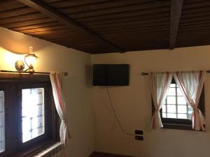 a room with two windows and a flat screen tv at ЧОЛАКОВАТА КЪЩА in Koprivshtitsa