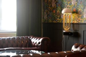 een woonkamer met een leren bank en een lamp bij Linnen Luxx Apartment in Berlijn