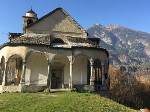 an old house on a hill with a mountain in the background at Hotel Domodossola in Domodossola