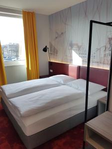 1 dormitorio con 2 camas y ventana grande en Campanile Leipzig Halle Airport en Leipzig