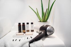 a black hair dryer next to cosmetics and a plant at Alunia Incognito Suites - Adults Only in Pirgos