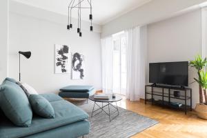 a living room with a blue couch and a tv at Acropolis Core Bright & Modern Apartment by UPSTREET in Athens